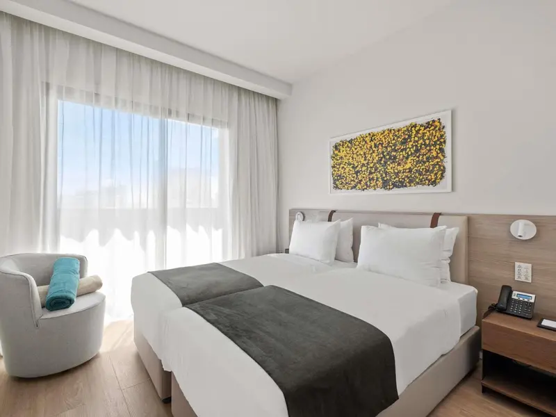 Une chambre lumineuse avec un grand lit et un fauteuil.
