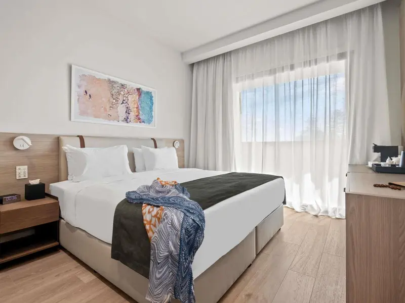Une chambre lumineuse avec un grand lit et un tableau décoratif.