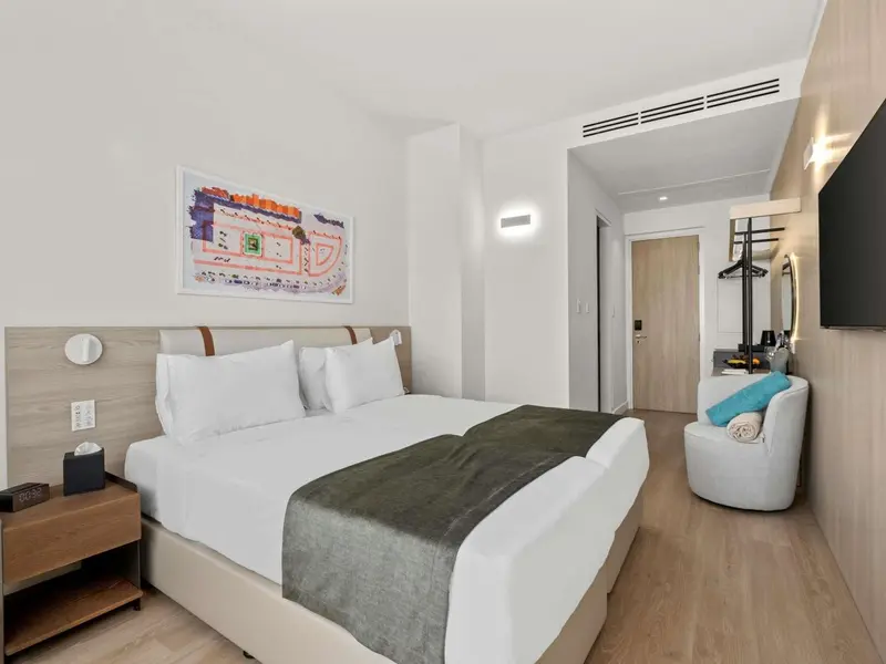 Une chambre lumineuse avec un grand lit et un fauteuil.