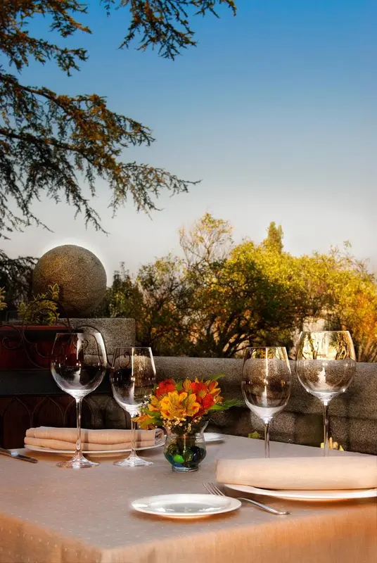 Une table dressée avec des verres à vin et une composition florale sur une terrasse en pierre.