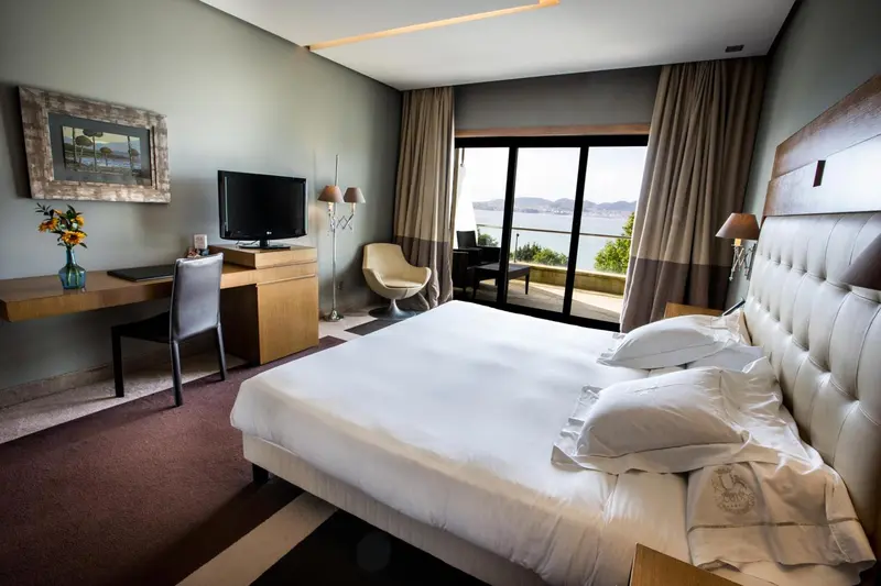 Chambre lumineuse avec un grand lit et une vue sur la mer.