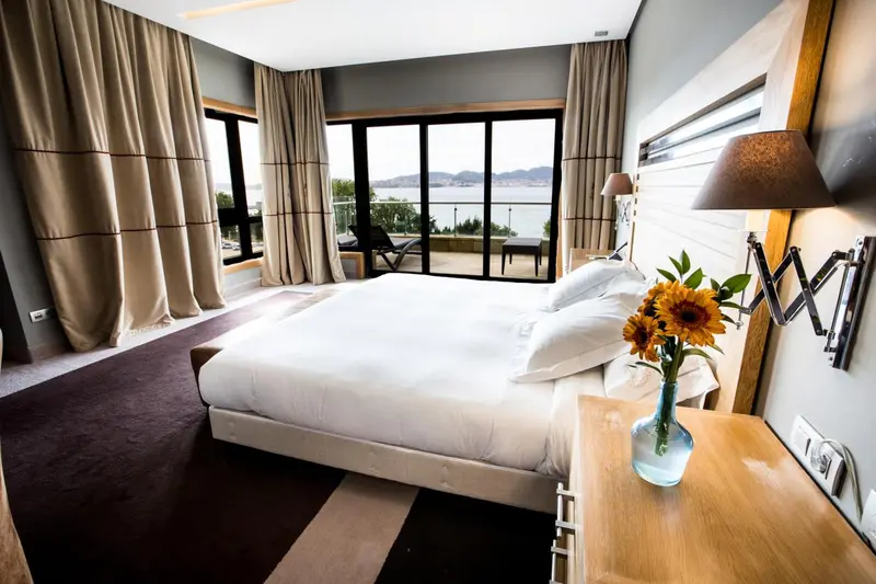 Chambre lumineuse avec un grand lit et une vue sur la mer.