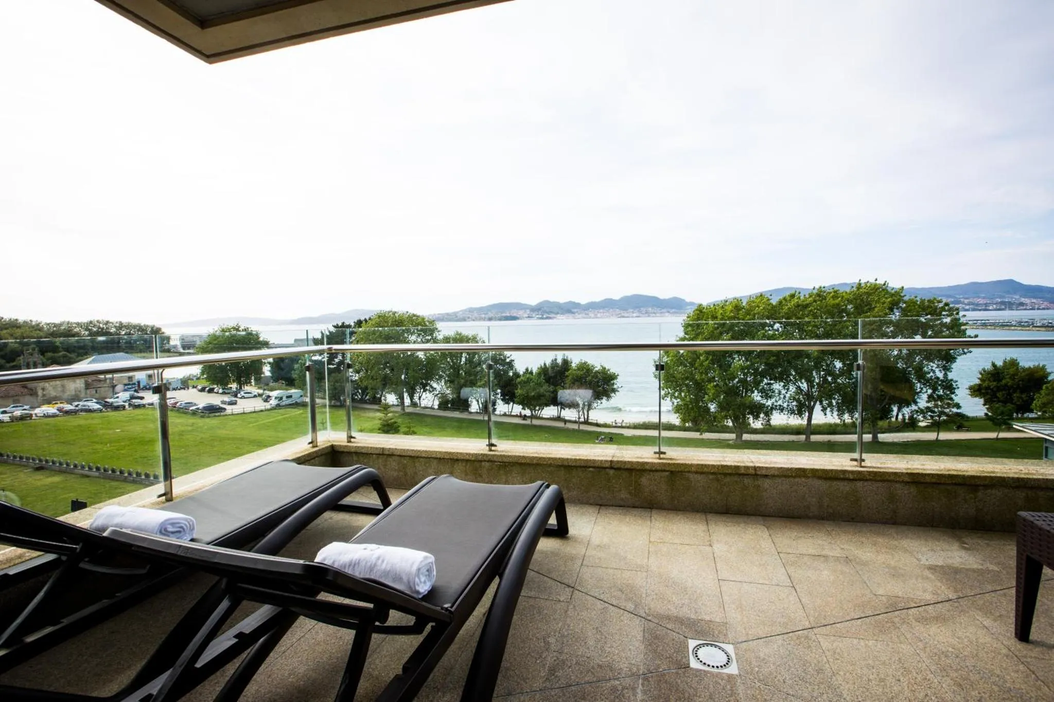 Deux transats sur une terrasse avec vue sur la mer et les montagnes.