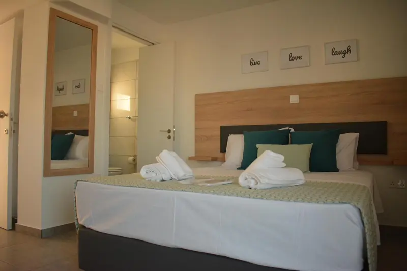 Une chambre lumineuse avec un grand lit recouvert de coussins et de couvertures blanches.