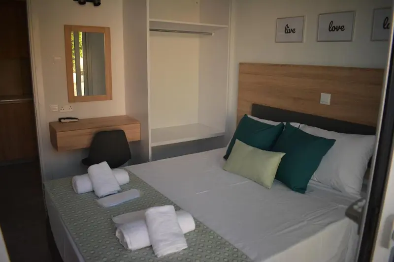 Une chambre lumineuse avec un lit fait et des coussins verts.