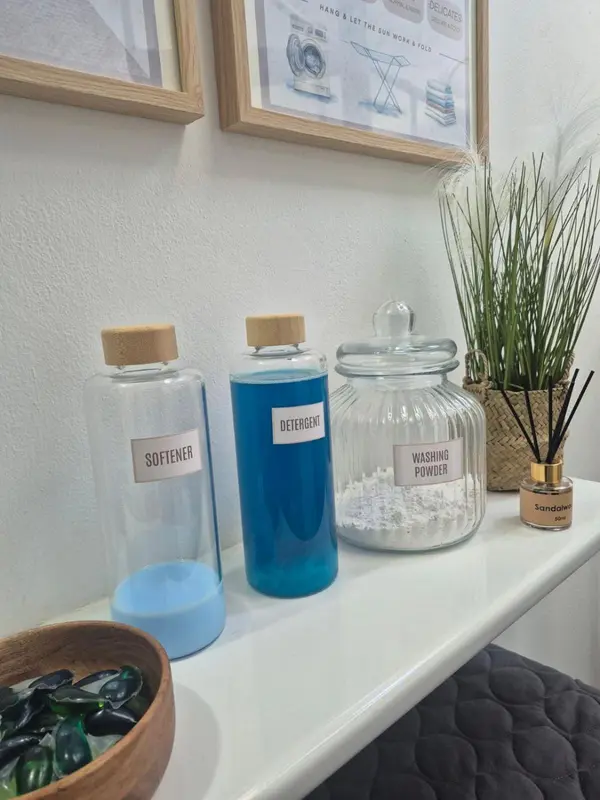 Des produits de lessive sont disposés sur une étagère blanche.