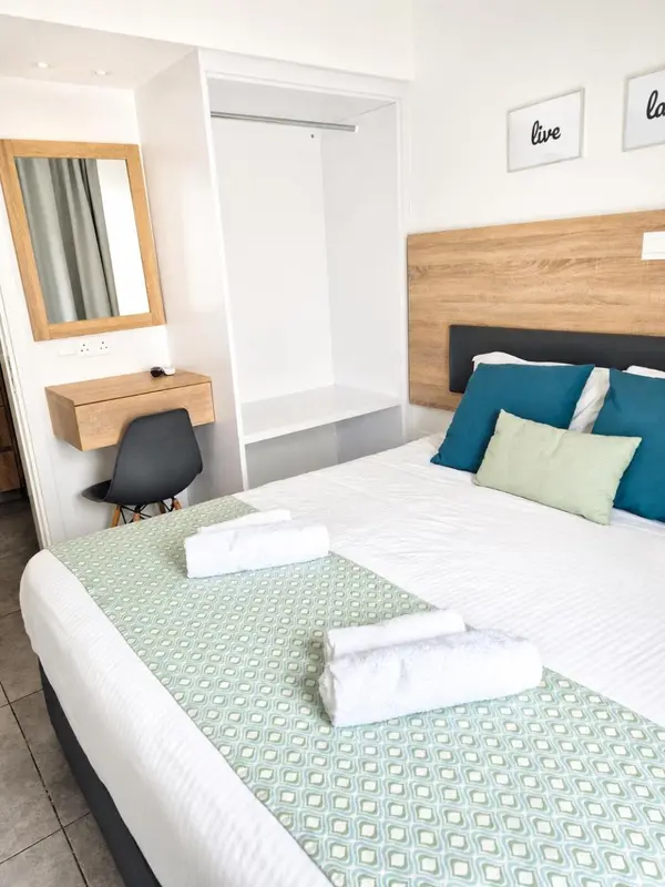 Une chambre lumineuse avec un lit recouvert d'une courtepointe à motifs et un bureau.