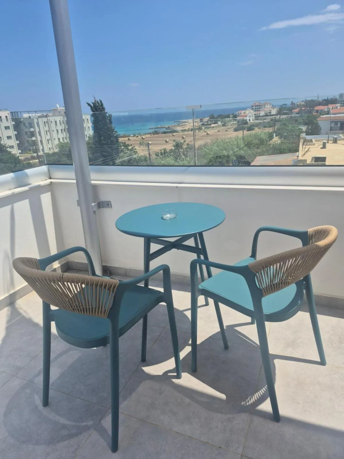 Terrasse avec table et chaises donnant sur la mer.