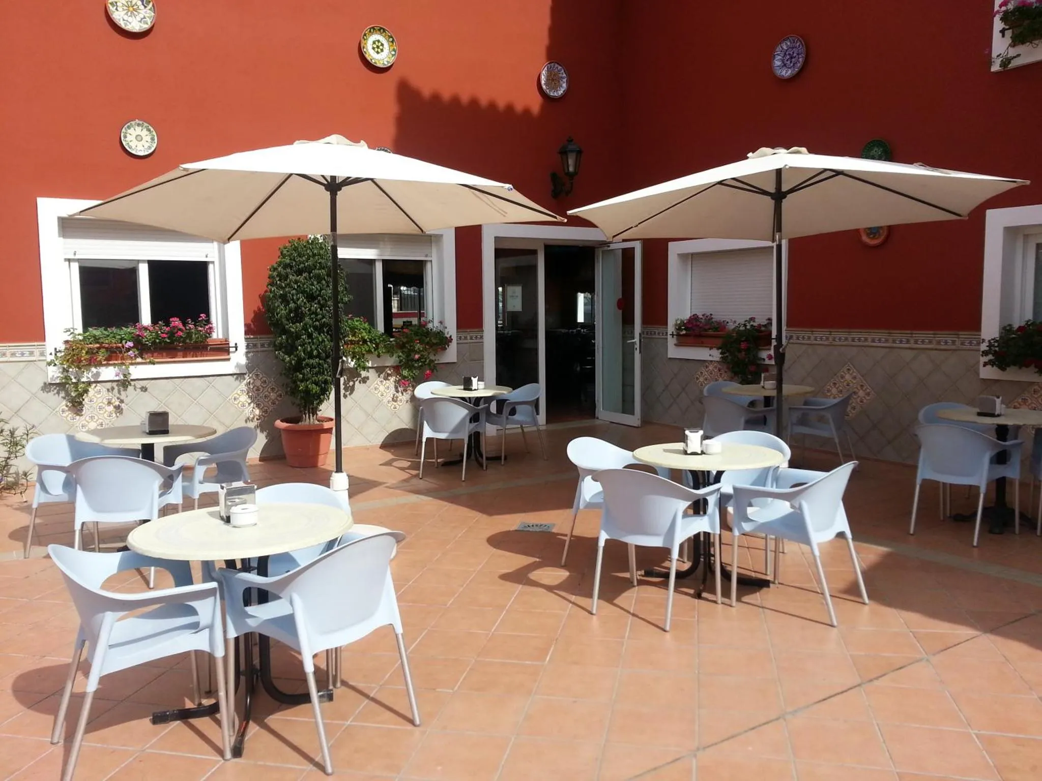 Terrasse ombragée avec tables et chaises en plastique bleu.