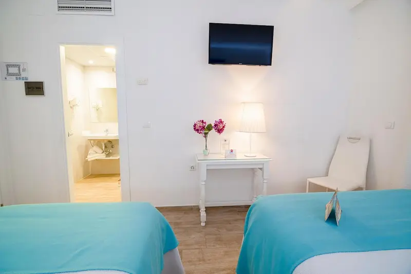 Une chambre lumineuse avec deux lits et un accès à une salle de bain.