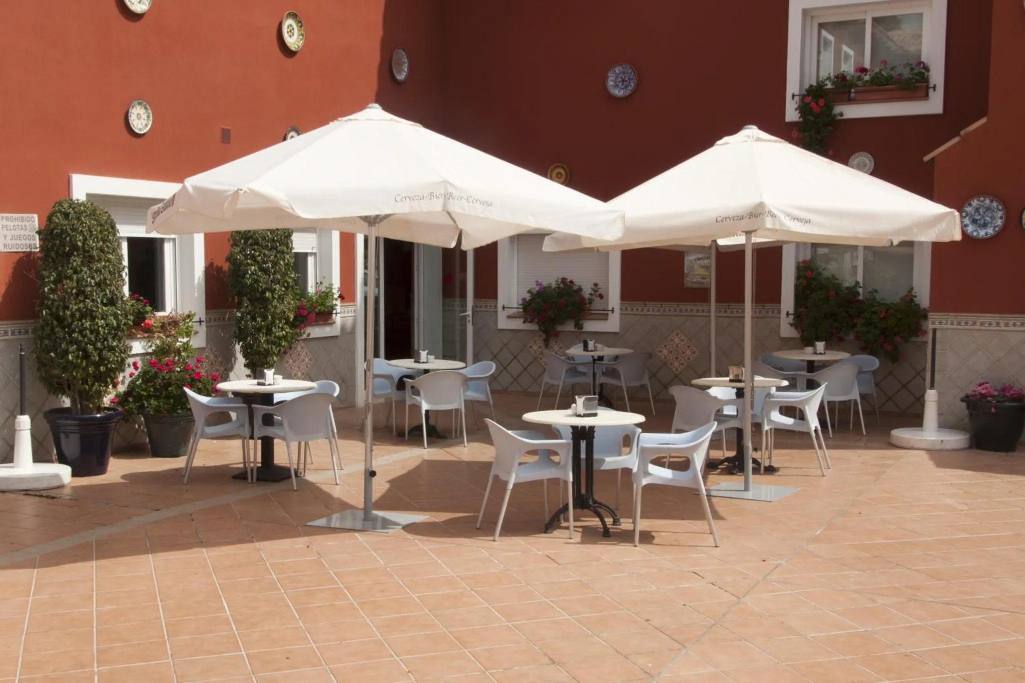 Terrasse ombragée avec tables et chaises en plastique.