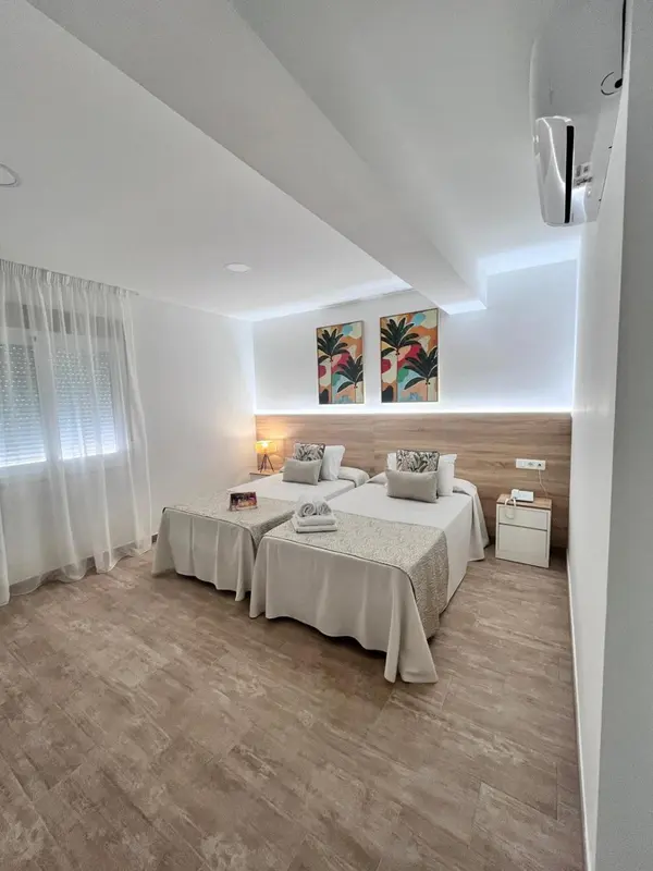 Chambre lumineuse avec deux lits simples et décoration tropicale.