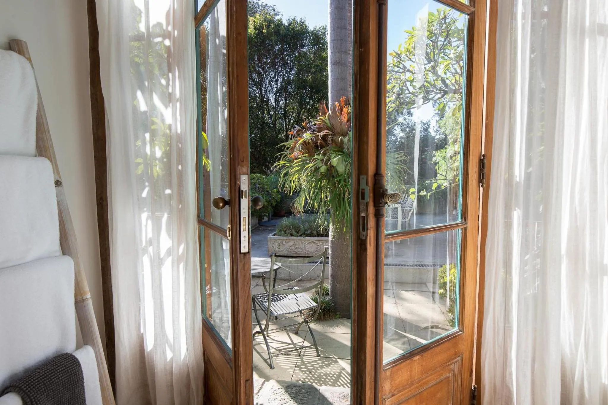 Vue sur une terrasse verdoyante à travers des portes-fenêtres ouvertes.