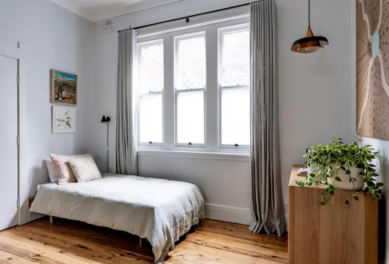 Une chambre lumineuse avec un lit simple et une décoration sobre.