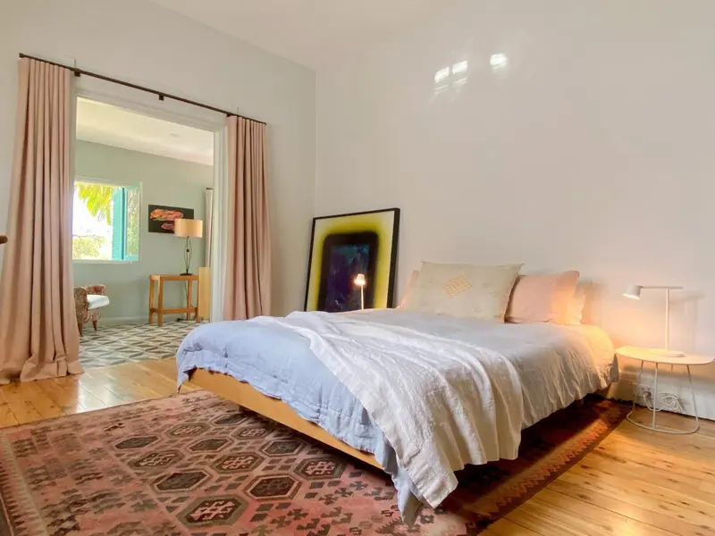 Une chambre lumineuse avec un grand lit et un tapis coloré.