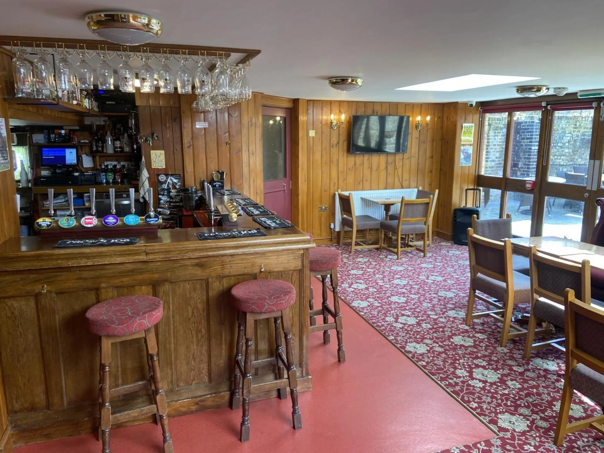 Un comptoir de bar en bois avec des tabourets, dans une salle au décor chaleureux.