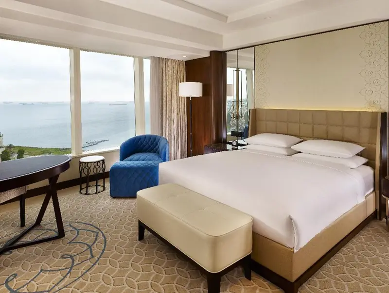 Chambre lumineuse avec un grand lit et une vue sur la mer.