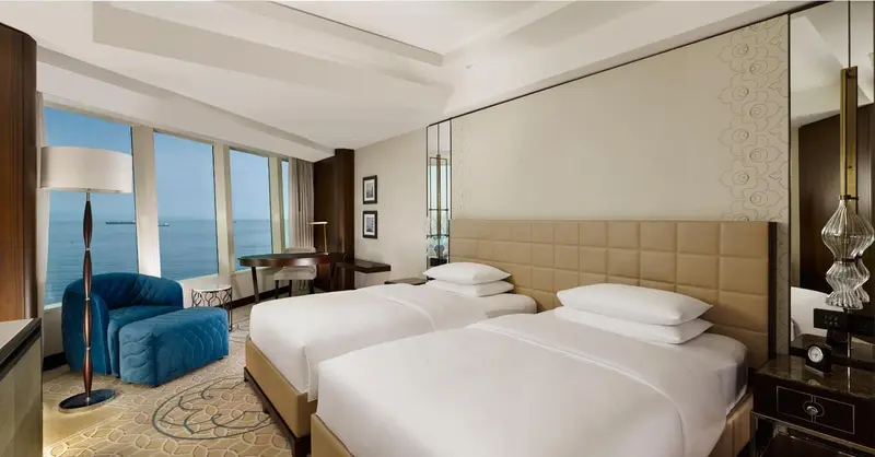 Une chambre lumineuse avec deux lits simples et une vue sur la mer.