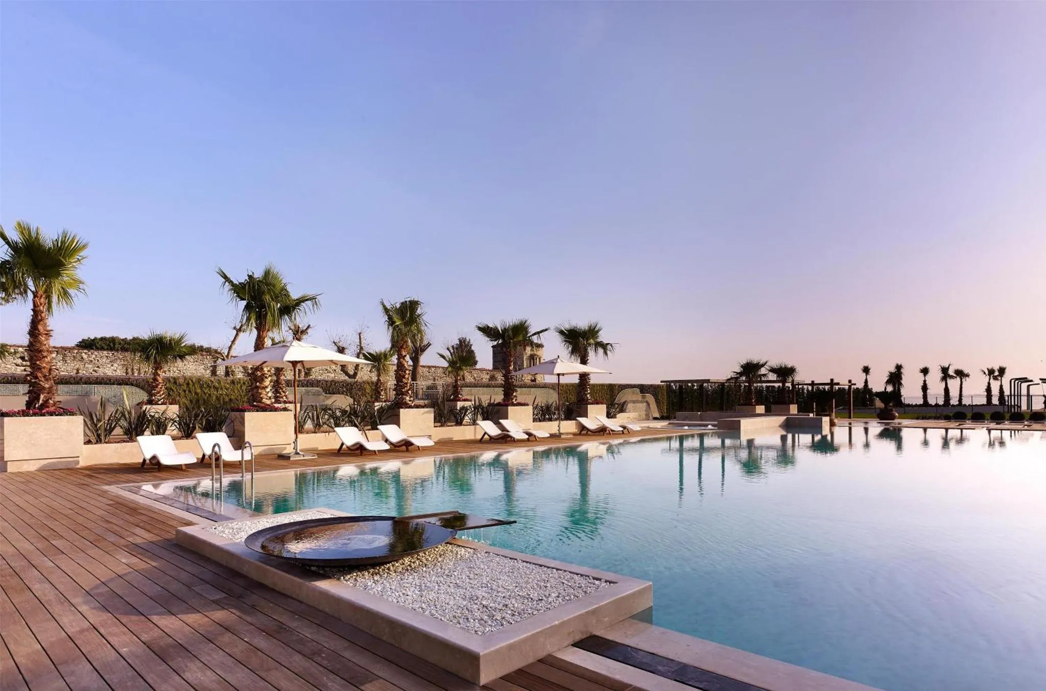 Terrasse avec transats et piscine au bord de l'eau.
