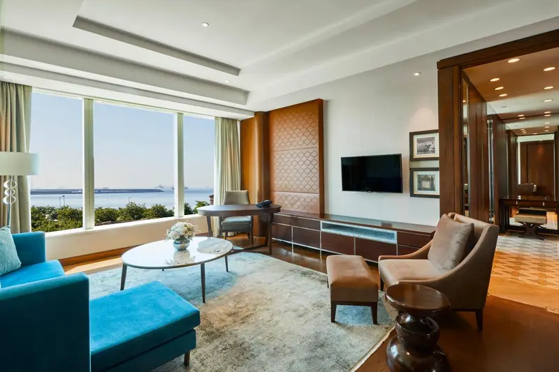 Un salon lumineux avec canapés et vue sur la mer par de grandes fenêtres.