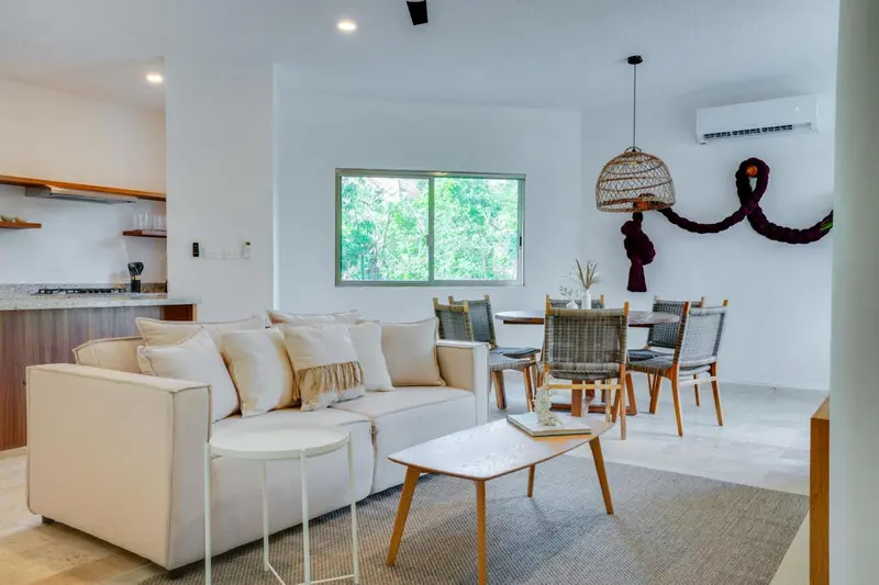 Espace de vie lumineux avec canapé, table à manger et cuisine ouverte.