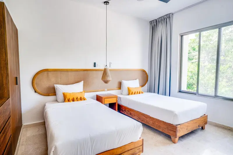 Une chambre lumineuse avec deux lits simples et une décoration sobre.