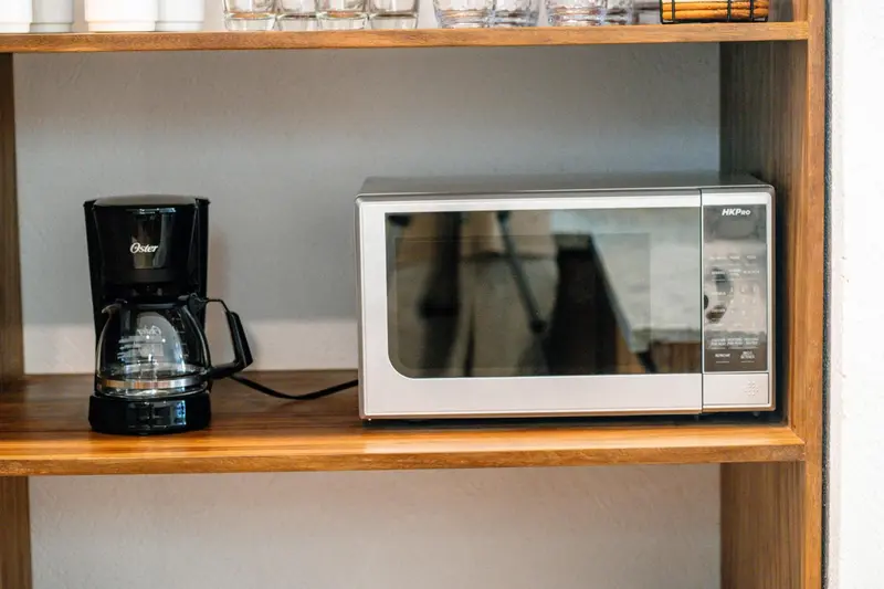 Une cafetière et un micro-ondes sont posés sur une étagère en bois.