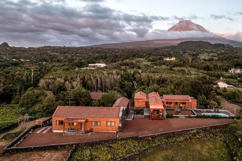 Vue aérienne de bâtiments aux toits rouges au milieu d'un paysage verdoyant et volcanique.