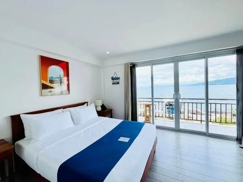 Une chambre lumineuse avec un grand lit donnant sur une vue mer.