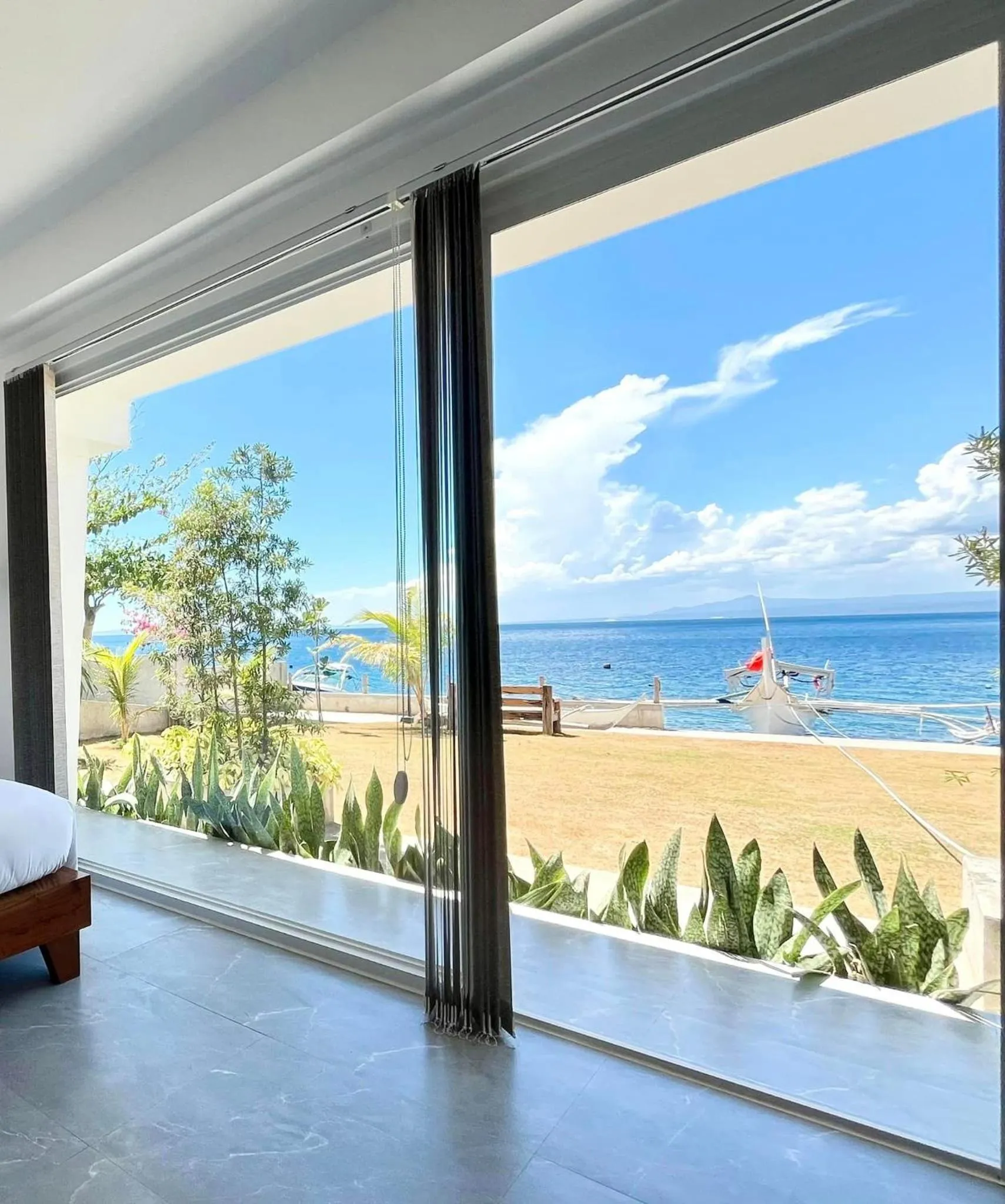 Vue sur la mer depuis une chambre avec de grandes baies vitrées.