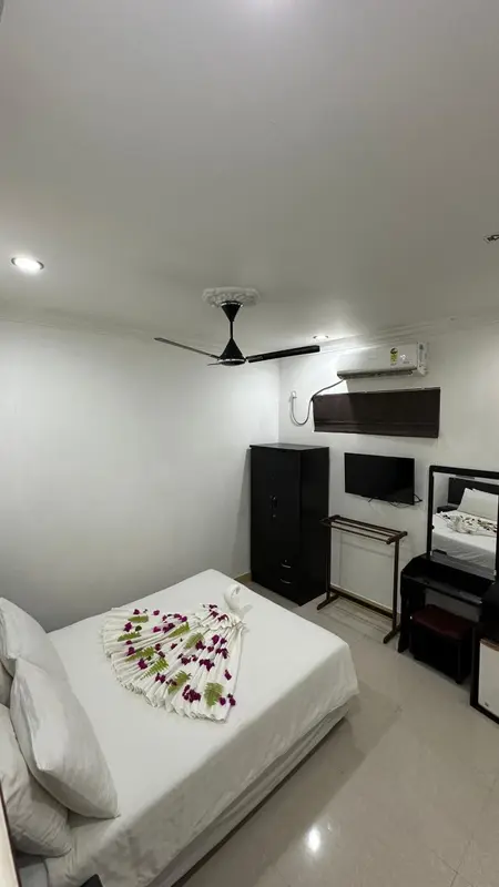 Une chambre lumineuse avec un lit décoré de fleurs et un meuble noir.