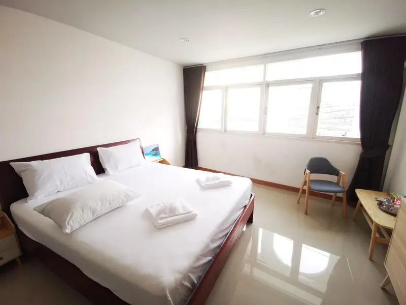 Une chambre lumineuse avec un grand lit recouvert de draps blancs et une chaise.