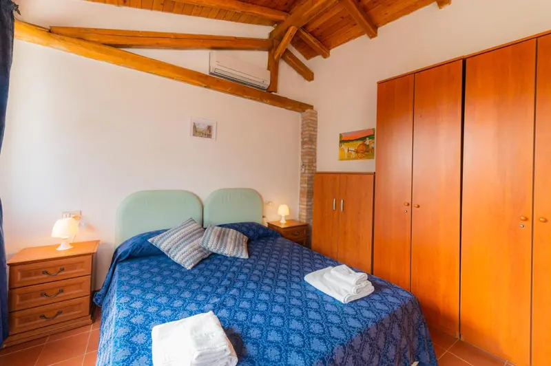Une chambre lumineuse avec un lit recouvert d'une couverture bleue et de coussins.