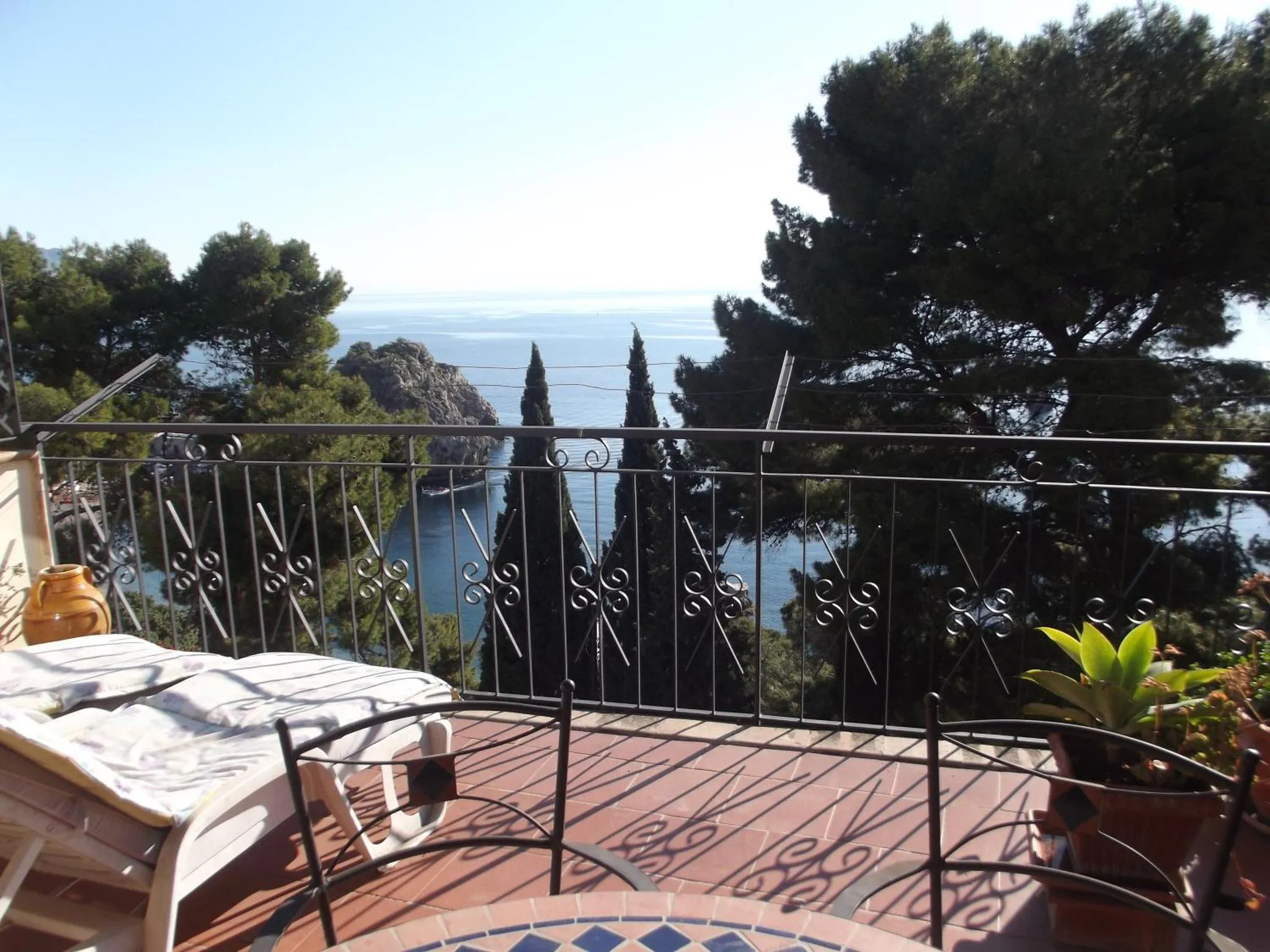 Terrasse carrelée avec transats donnant sur la mer et la végétation.