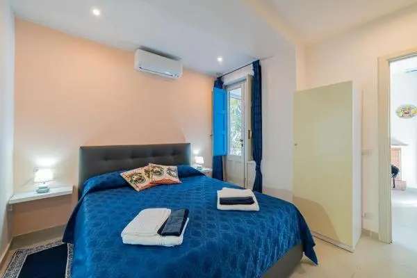Une chambre lumineuse avec un lit fait et une porte-fenêtre ouverte.