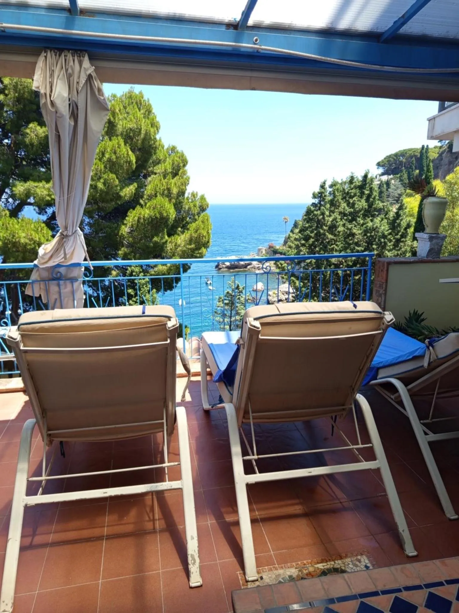 Deux transats invitent à la détente sur une terrasse ensoleillée avec vue sur la mer.