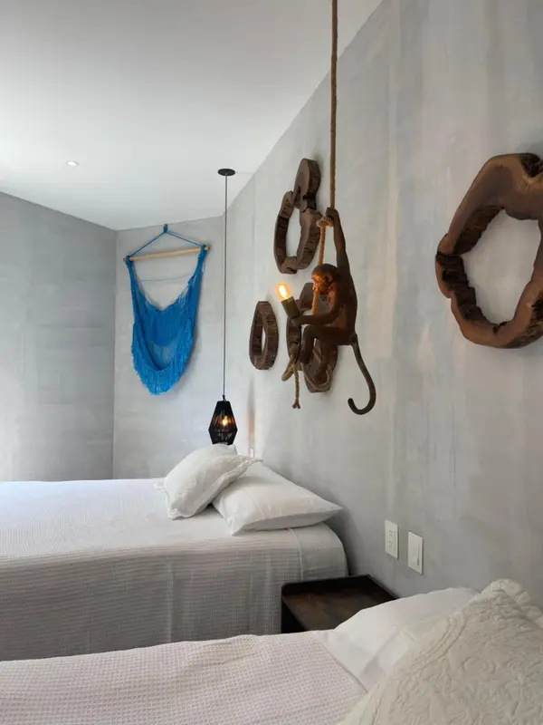 Une chambre lumineuse avec deux lits simples et une décoration murale originale.