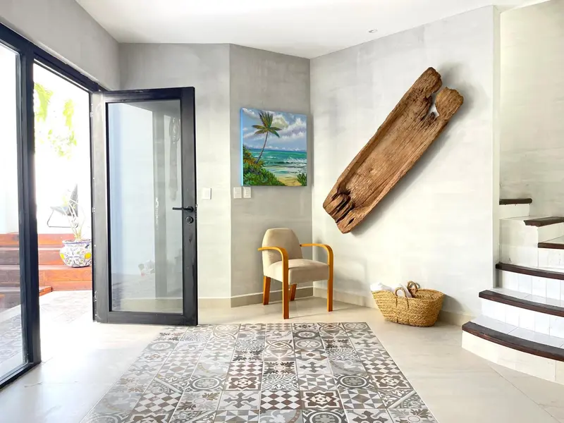 Une chaise est placée devant une œuvre d'art murale dans un hall d'entrée lumineux.
