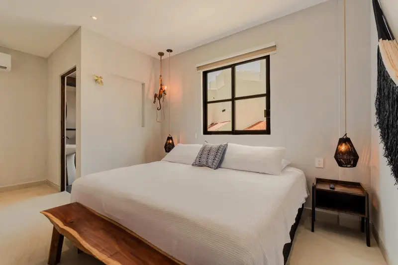 Une chambre lumineuse avec un grand lit recouvert d'un couvre-lit blanc.