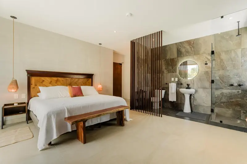 Une chambre lumineuse avec un grand lit et une salle de bain ouverte.