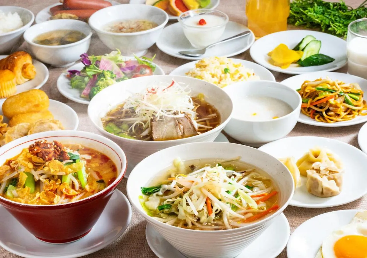 Table garnie de divers plats asiatiques, notamment des soupes, des nouilles et des accompagnements.