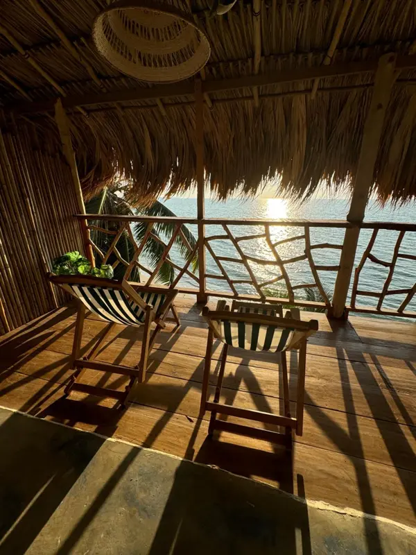 Terrasse en bois avec mobilier d'extérieur donnant sur la mer au coucher du soleil.
