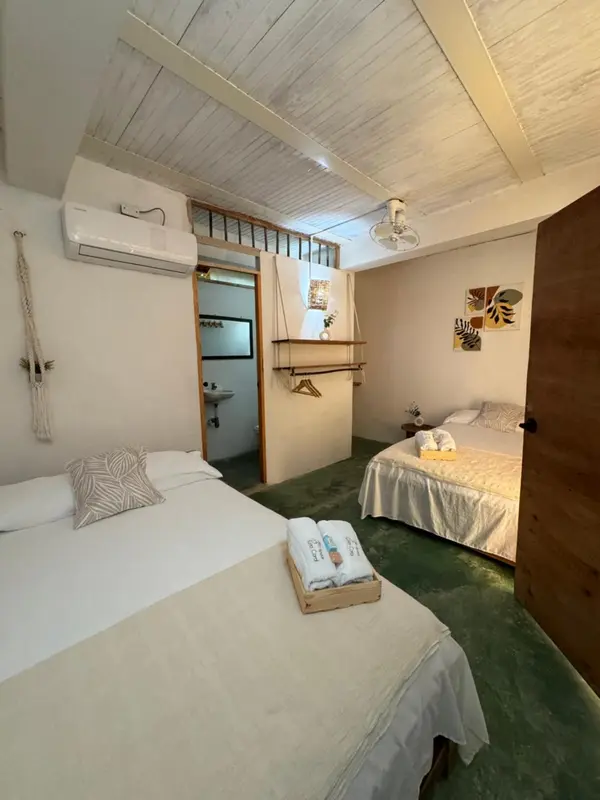 Une chambre lumineuse avec deux lits simples et une salle de bain attenante.