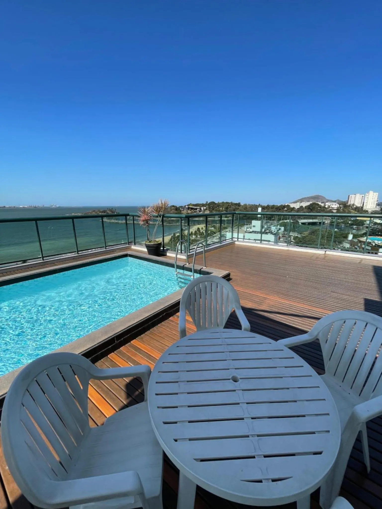 Terrasse avec piscine et mobilier de jardin offrant une vue sur la mer.