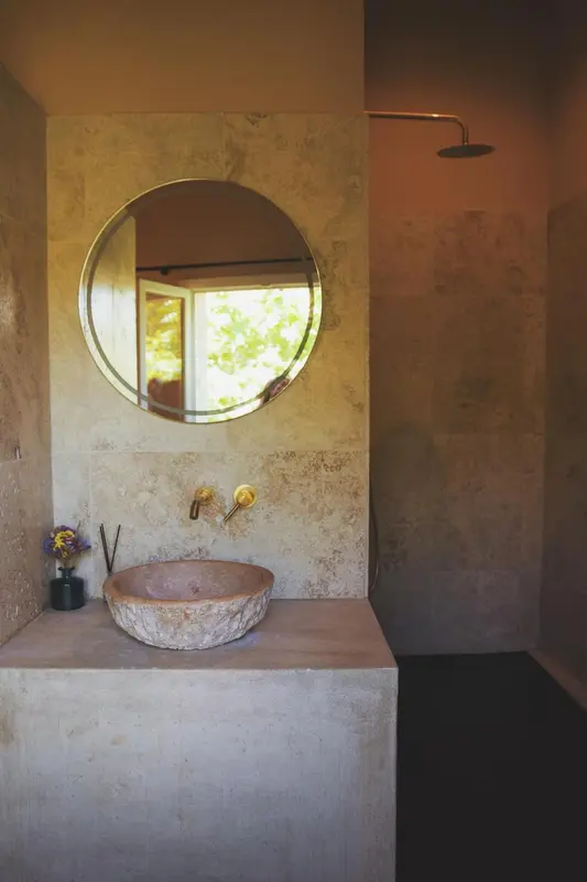 Une salle de bain avec une douche à l'italienne et un lavabo en pierre.