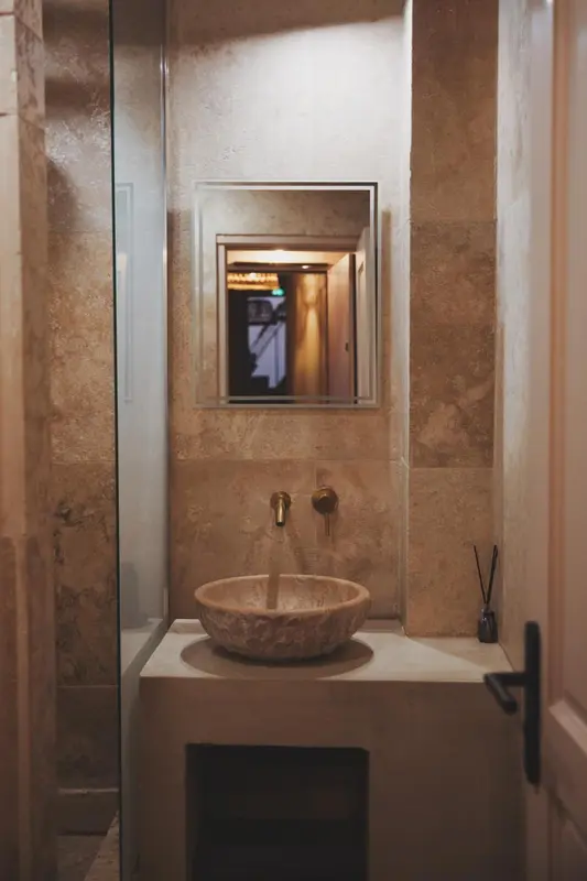 Un lavabo en pierre est installé dans une petite salle de bain carrelée.
