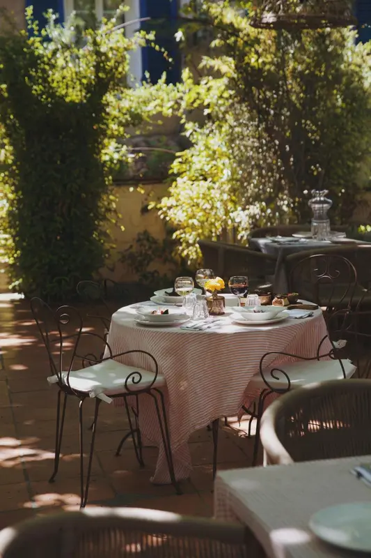 Une table dressée pour un repas en extérieur, ombragée par la végétation.