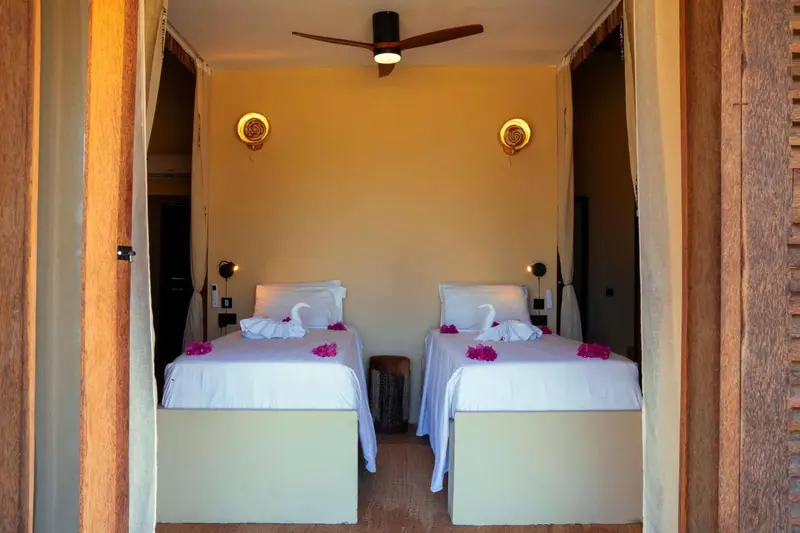 Deux lits simples préparés dans une chambre lumineuse.
