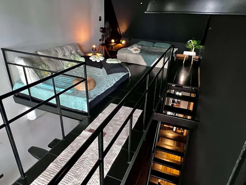 Vue d'une chambre en mezzanine avec lits et escalier.