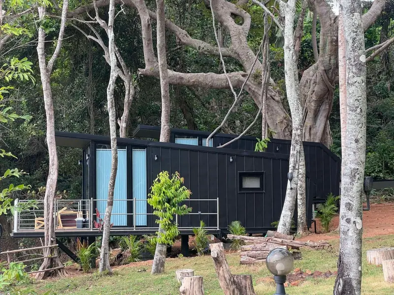 Une structure moderne sombre se fond dans un paysage tropical luxuriant.